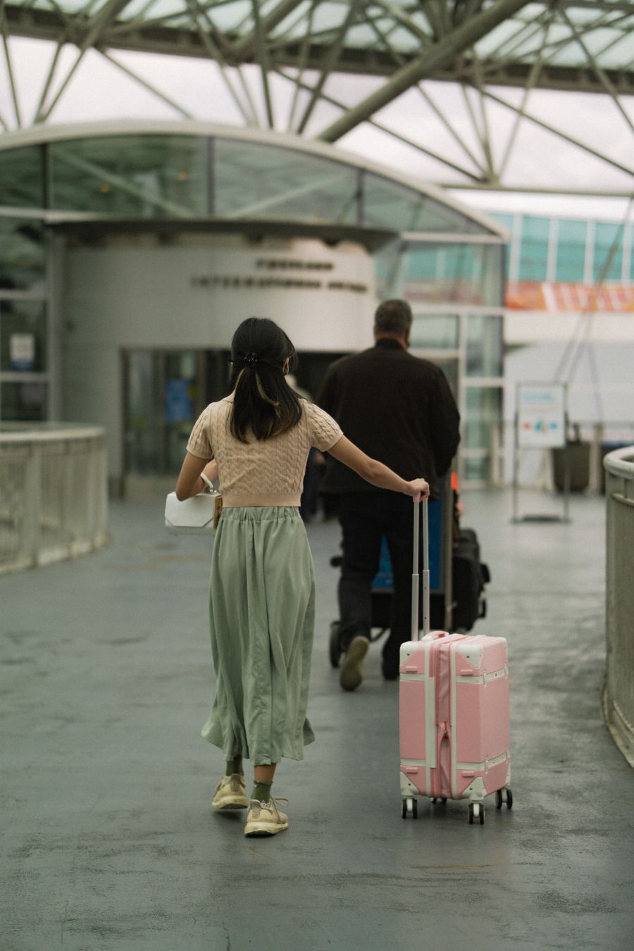 woman in brown t shirt pushing her pink luggage and man in black long sleeves pushing trolley — Developers · the Netherlands: Coast roads and country lanes — the map keeps up wherever you roam.