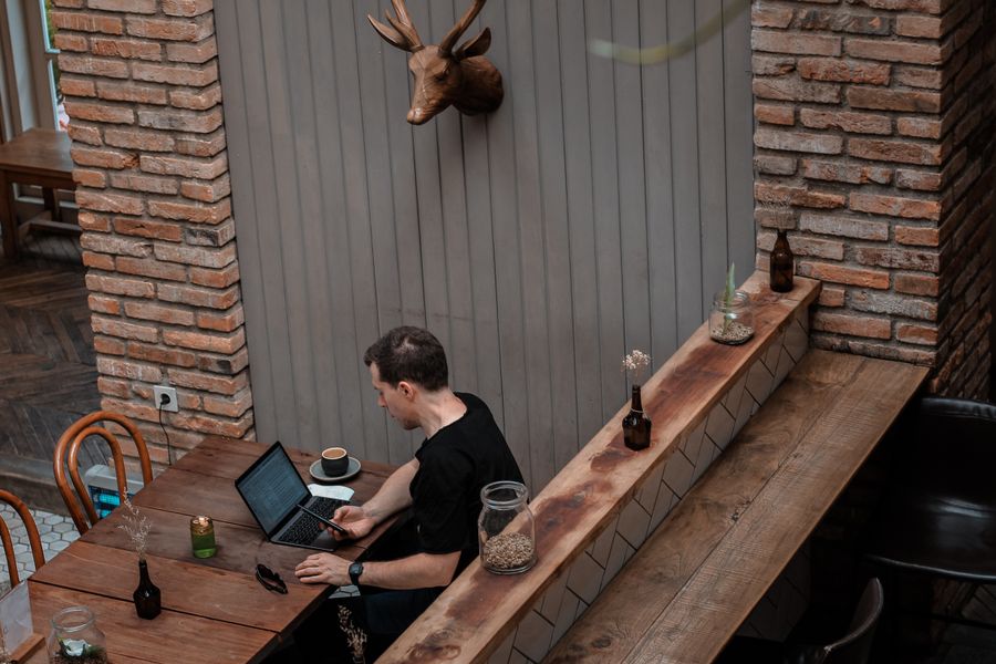 man sitting in front of his laptop white looking at his phone — Developers · Moldova: The commute, handled: podcasts downloaded, messages sent, no dead zones.
