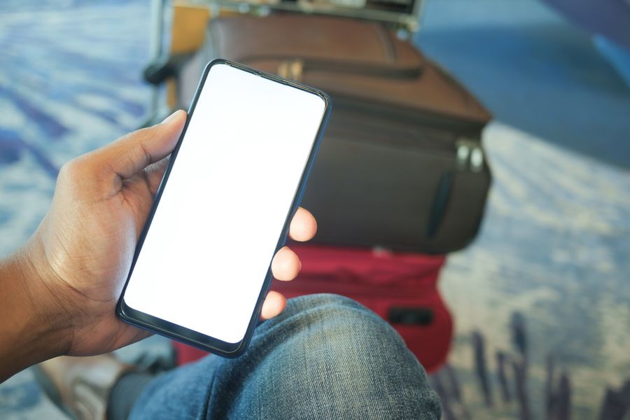 A person holding a smartphone in an airport with luggage visible, ideal for travel and tech concepts. — Developers · Indonesia: Street-food stalls and mobile pay: dinner ordered without a word of the language.