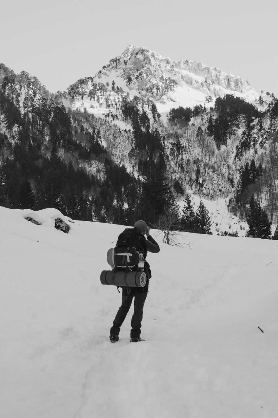 back view of a person with a backpack hiking in snowy mountains — Developers · the United Kingdom: The window seat office: emails sent somewhere over the ocean.
