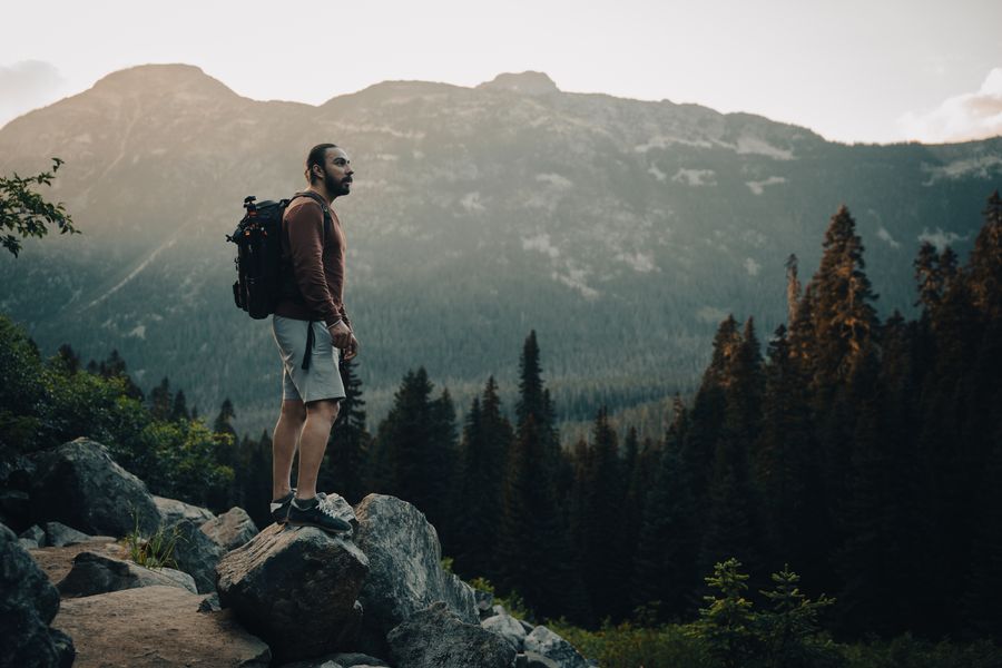 man with a backpack standing on a rock — Developers · Switzerland: The window seat office: emails sent somewhere over the ocean.
