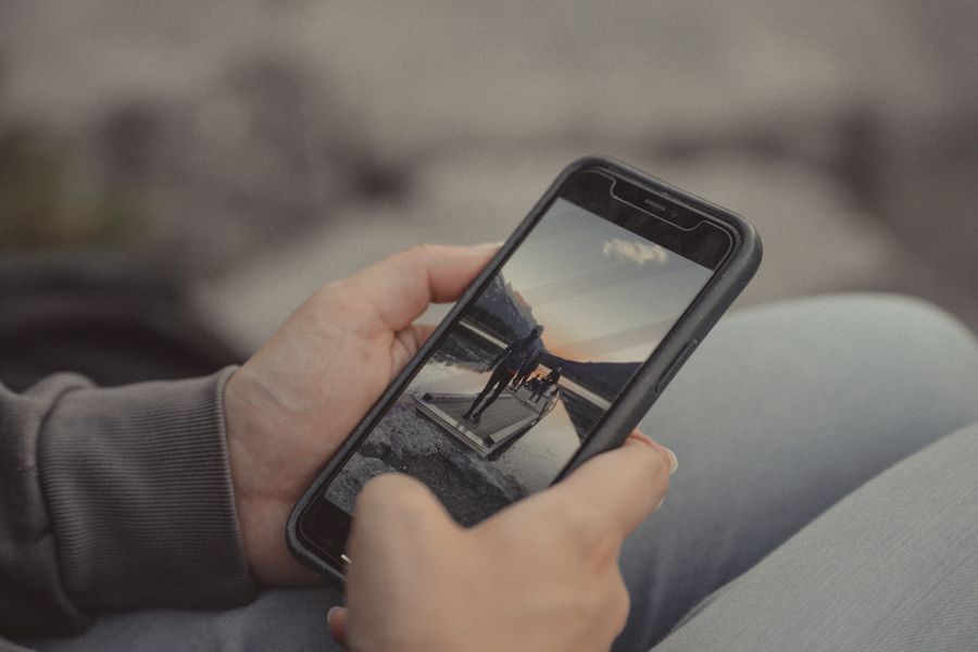 Close-up of hands holding a smartphone showing a mountain scene, captured outdoors in Banff. — Developers · Italy: Real journeys, real connectivity — this is what the product is for.