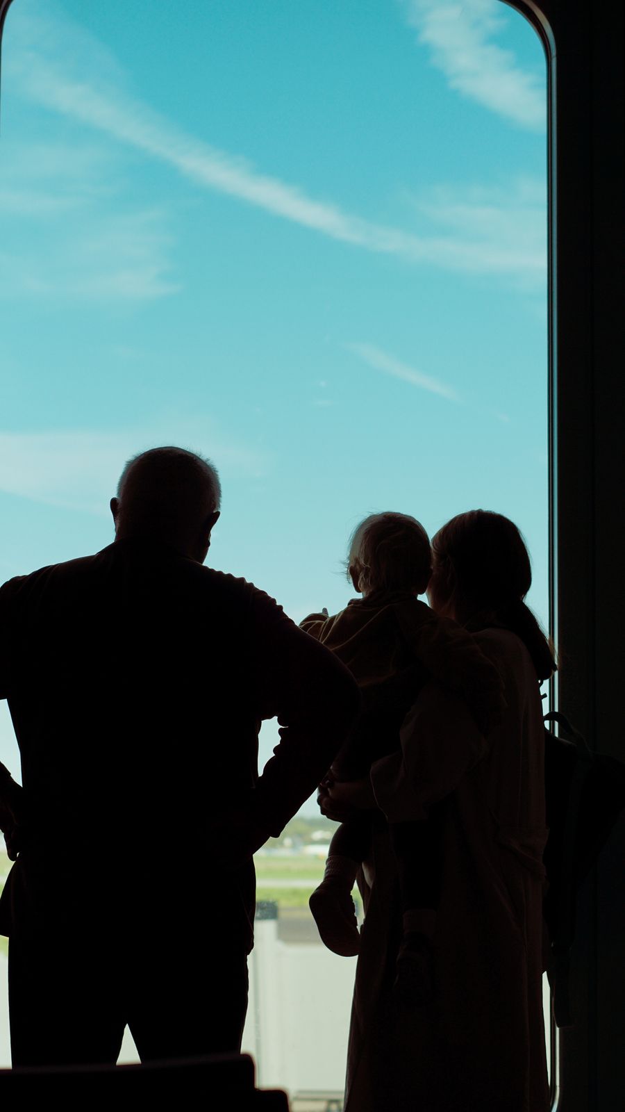 silhouette of a family looking out of a window at an airplane — Developers · Albania: The business trip: client deck synced, video call joined from the taxi.