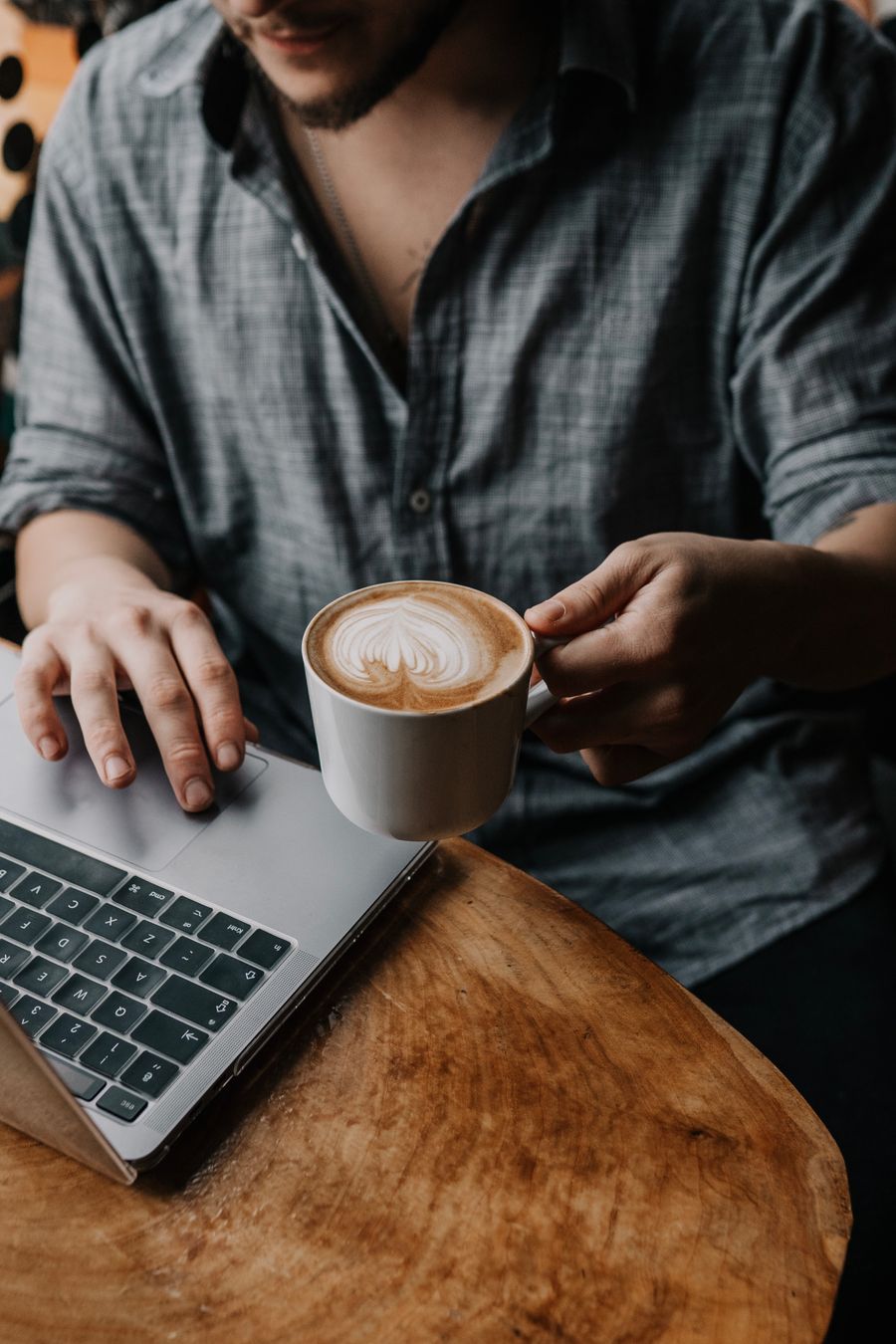 man with coffee using laptop at cafe — Developers · Qatar: The business trip: client deck synced, video call joined from the taxi.