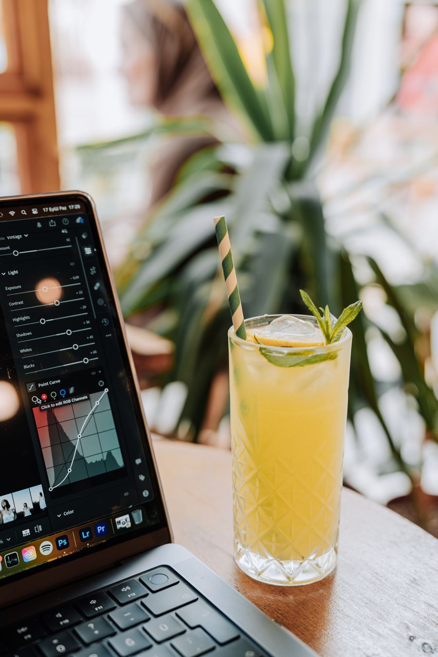 glass with a drink and a straw by a laptop