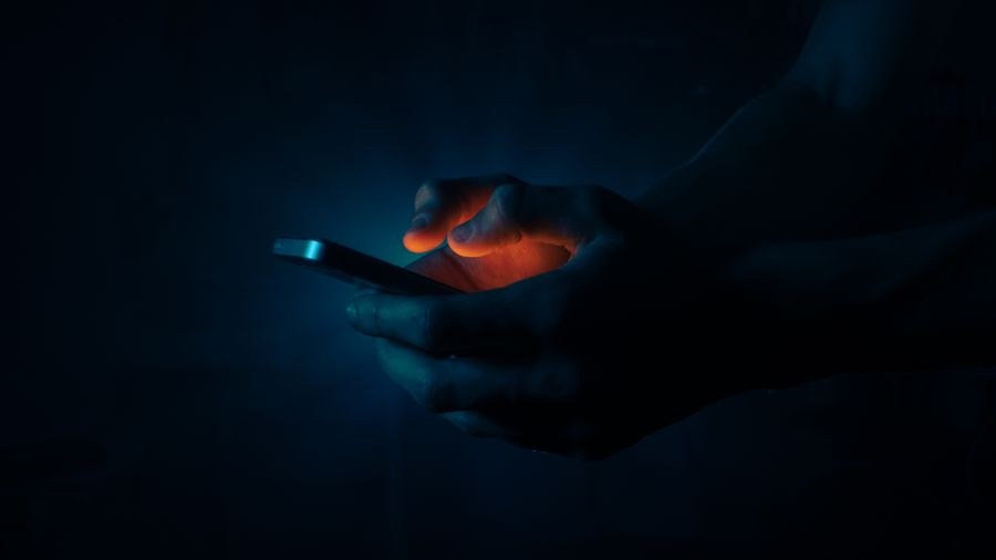 man holding a mobile phone in the dark — Developers · DR Congo: Sunrise hikes start with a weather check — data on, boots on.