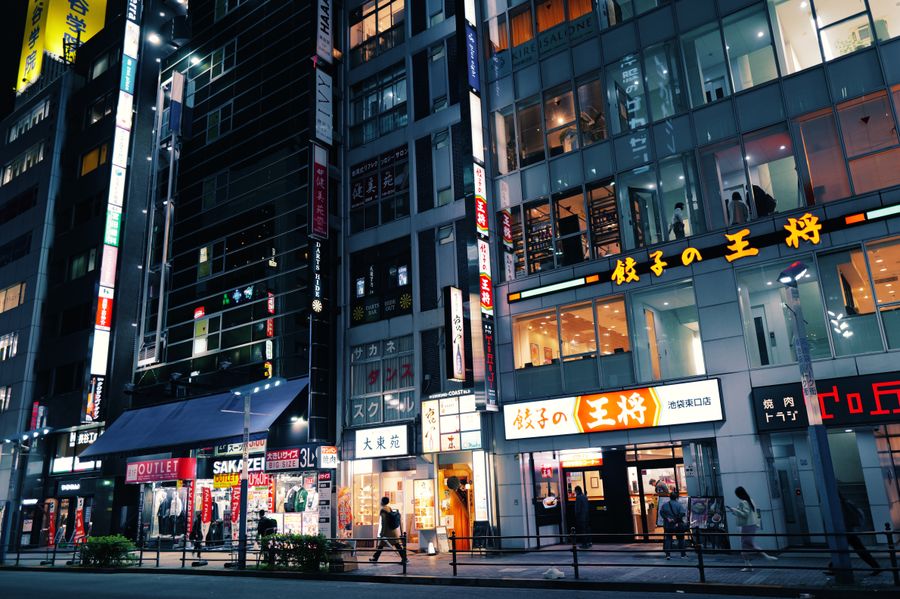 buildings and people in city at night — Terms: Duty-free browsing: price-checked against home before buying.
