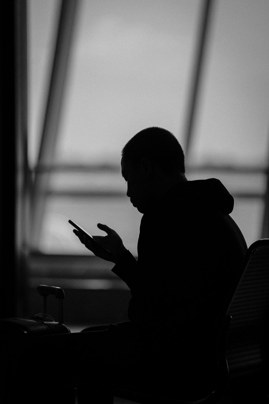 Silhouette of a man using a smartphone in an airport terminal in Surabaya, Indonesia. — Developers: The rental desk handshake: confirmation email open, license photo ready.