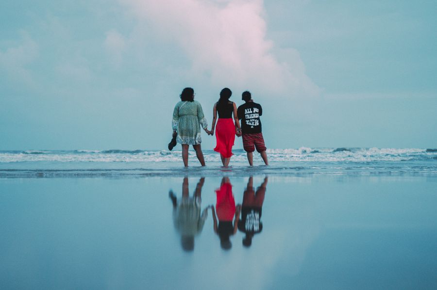 three people walking on the beach with the ocean in the background — Terms: Downtown, connected: the eSIM finds the fastest local network on its own.