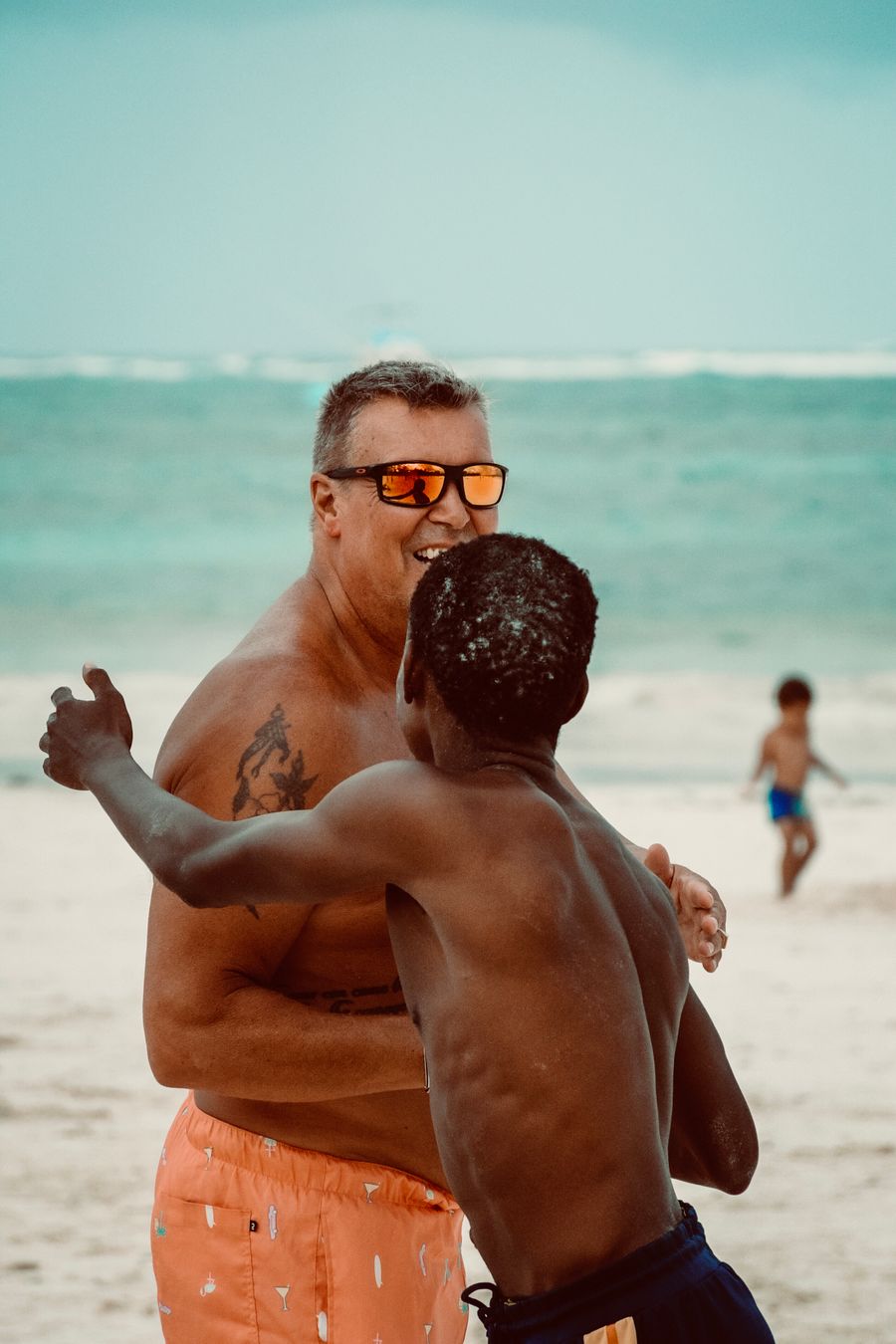a man in sunglasses and a shirt is standing on the beach with another man — Developers · Palestine: The long layover: streaming, working and messaging, all covered.