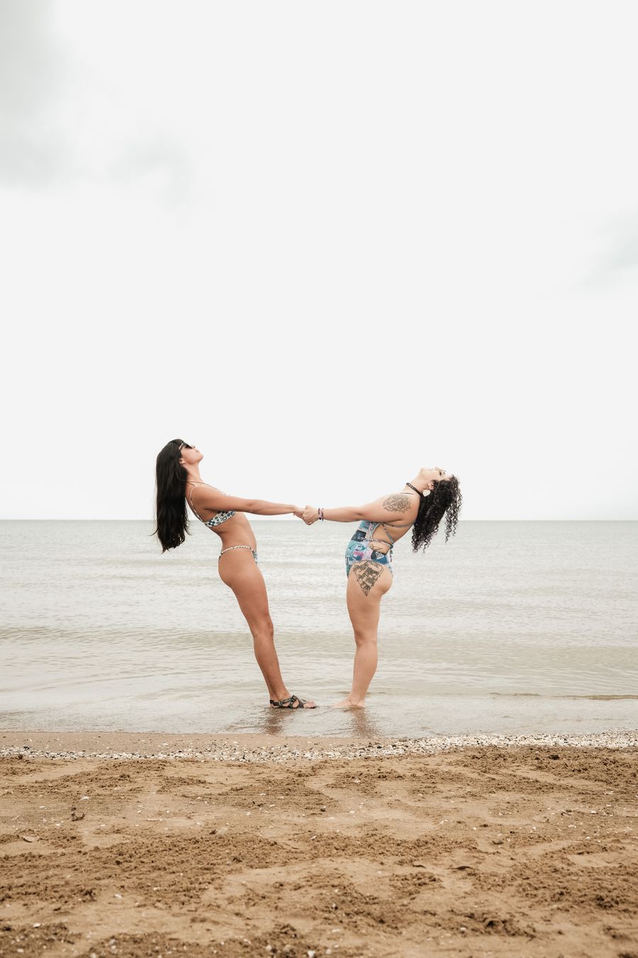 two women standing on the beach holding hands