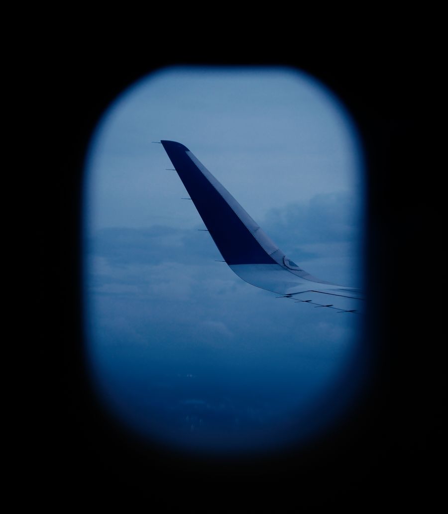 aerial view of airplane wing through window — Support: The group chat stays live across every border you cross.