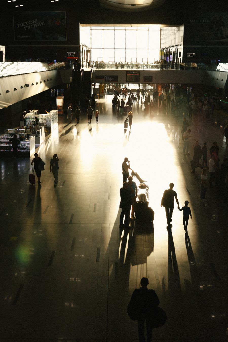 busy airport terminal with silhouetted travelers — Developers · Mali: The rental desk handshake: confirmation email open, license photo ready.