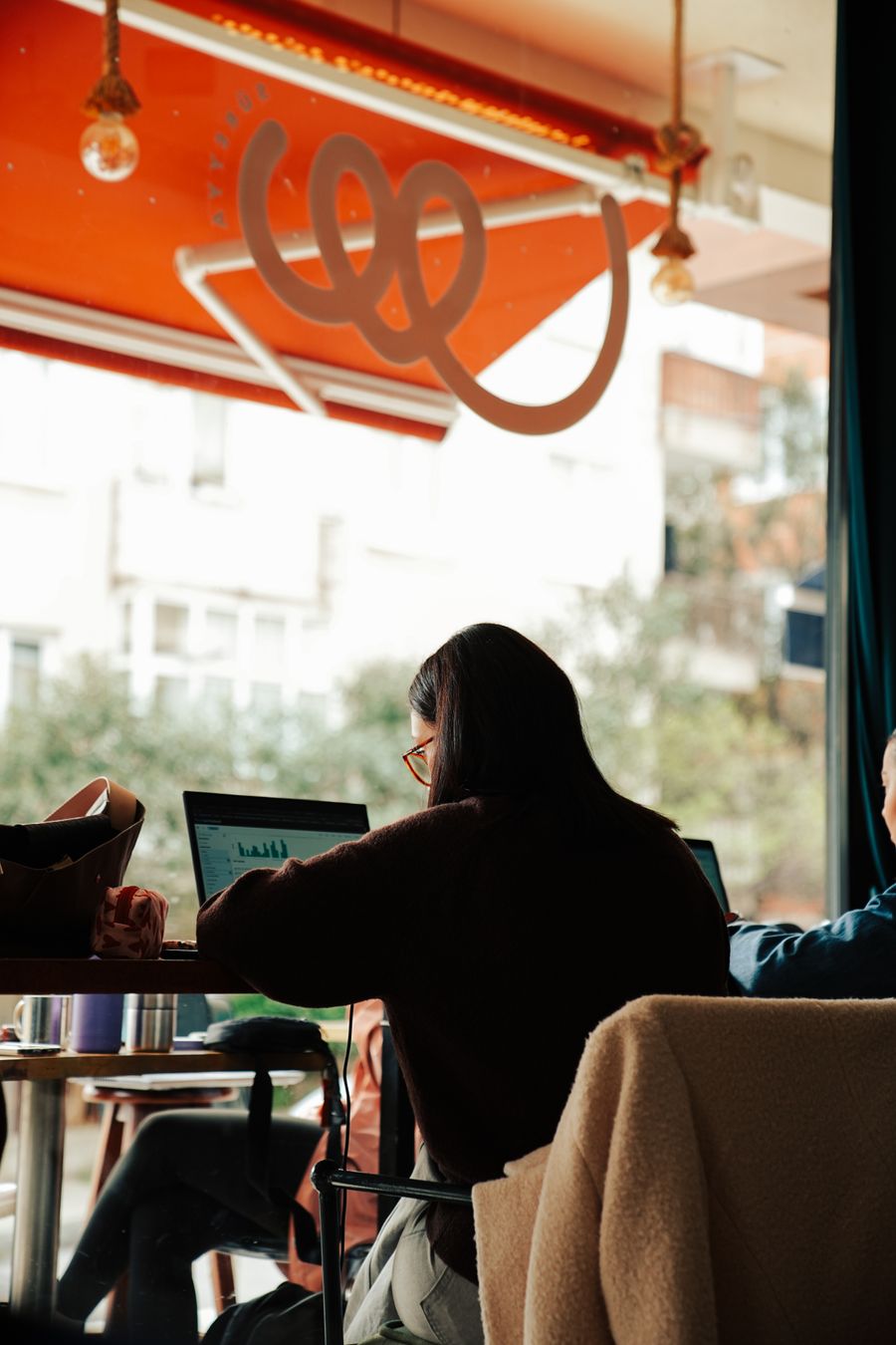 people working on laptops in a cozy cafe — Developers · Mali: The night bus: entertainment downloaded, messages queued, rest easy.