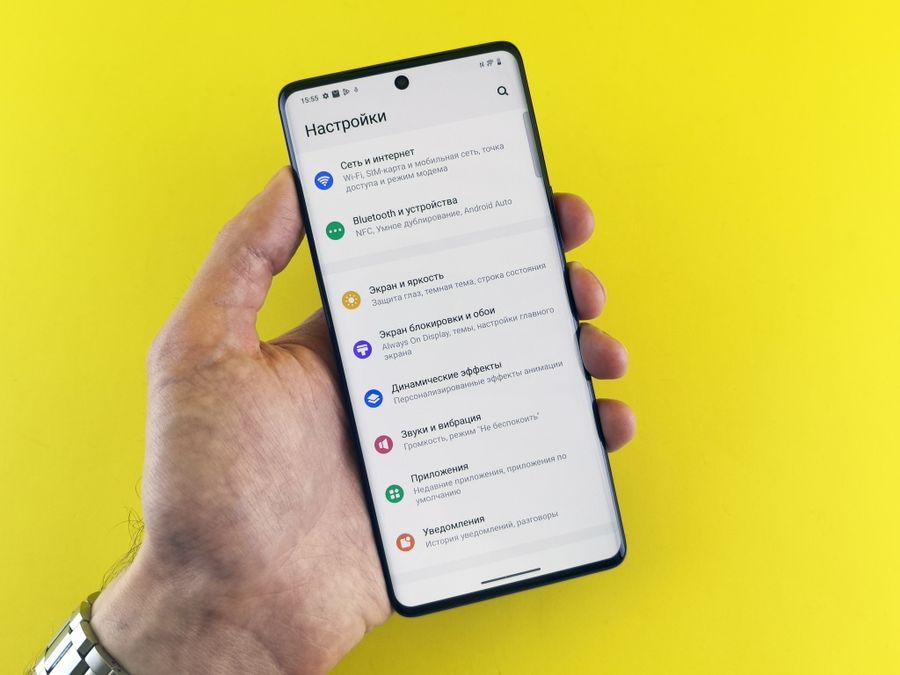 hand holding smartphone with settings menu displayed — Developers · Ecuador: One curl call provisions a Ecuador eSIM — 200 OK in milliseconds.