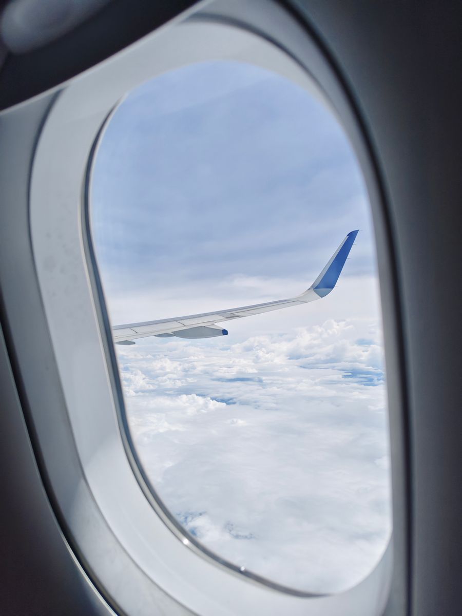 view of airplane wing and clouds from cabin — Developers · Greece: The window seat office: emails sent somewhere over the ocean.
