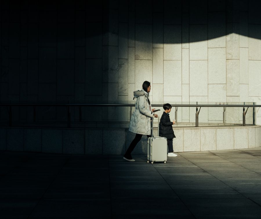 mother and child with suitcase walking indoors