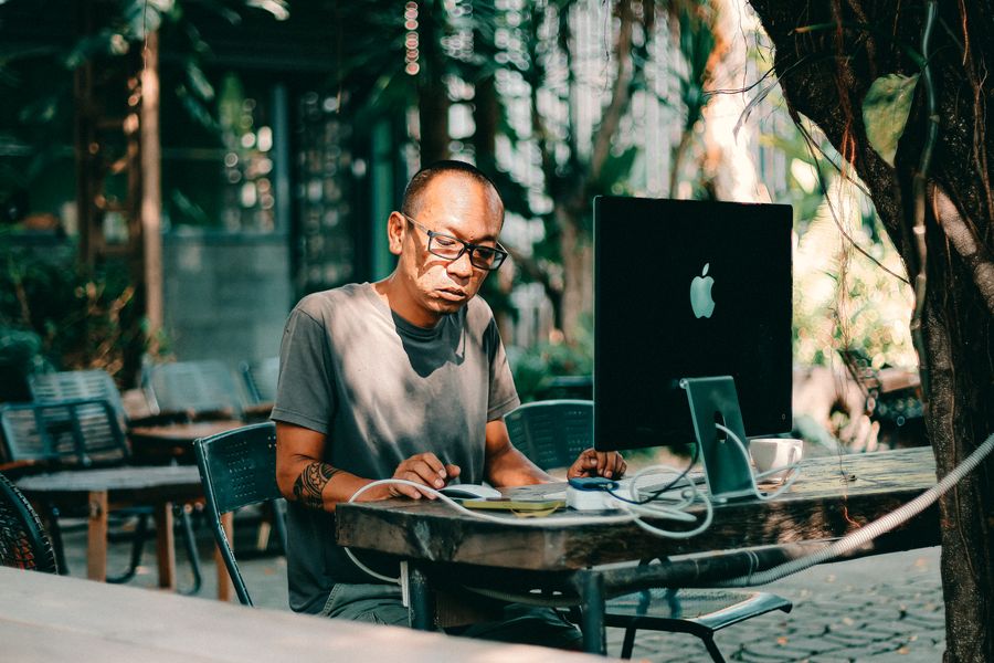man working on computer at outdoor cafe
