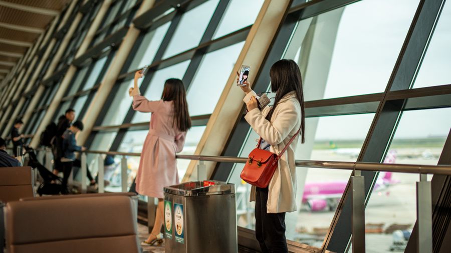 young travelers taking photos at shanghai airport — Developers · Suriname: The business trip: client deck synced, video call joined from the taxi.