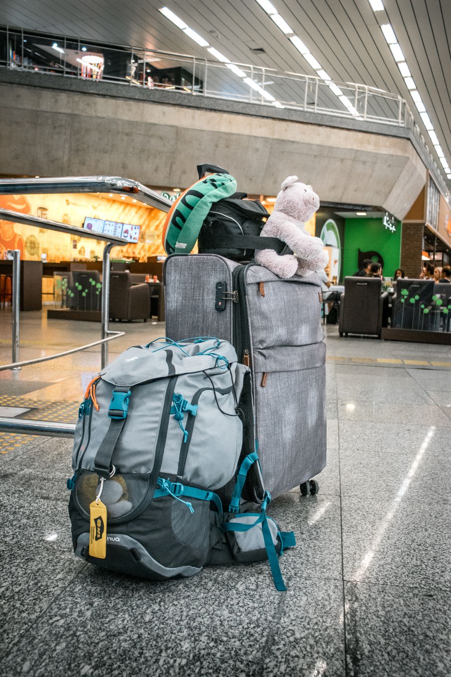 teddy bear sitting atop luggage left in airport
