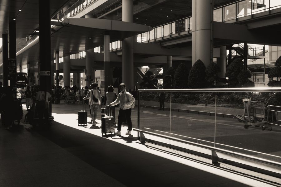 travelers with luggage at modern airport terminal — Developers · Italy: Platform to platform: tickets, timetables and taxis in one hand.