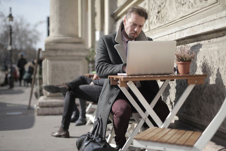 man in black jacket sitting on brown wooden folding chair using macbook — Developers · Mauritania: Duty-free browsing: price-checked against home before buying.