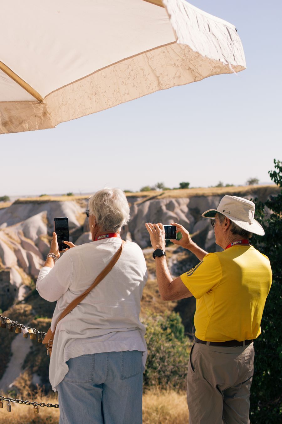 Senior tourists photographing scenic landscape in Cappadocia, Türkiye under a sun umbrella on a sunny day. — Developers · Papua New Guinea: The modern arrival: online before the seatbelt sign goes off.