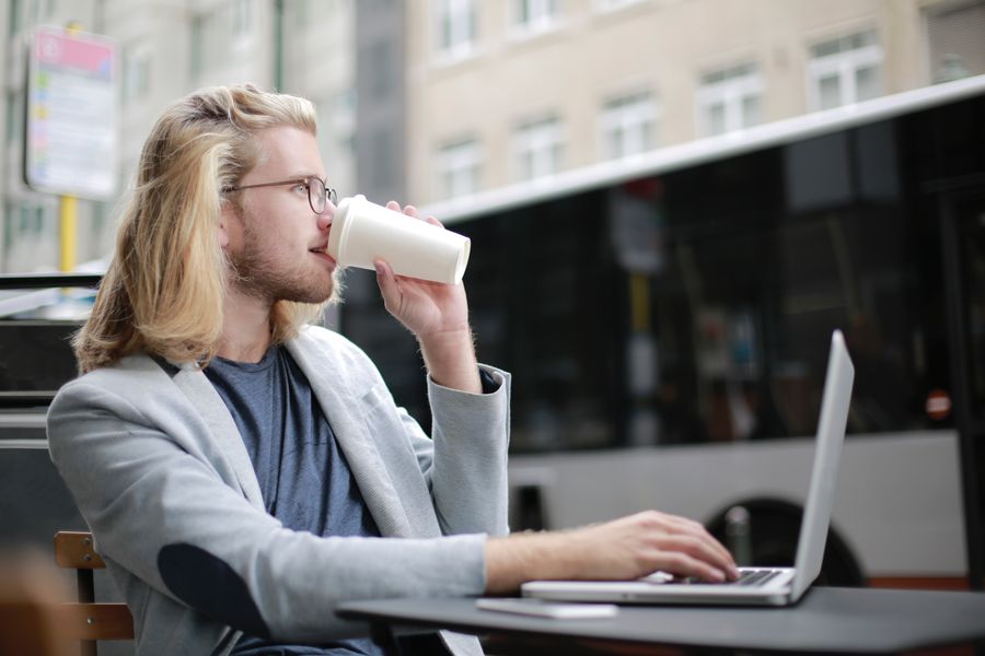 man drinking coffee while working on his laptop