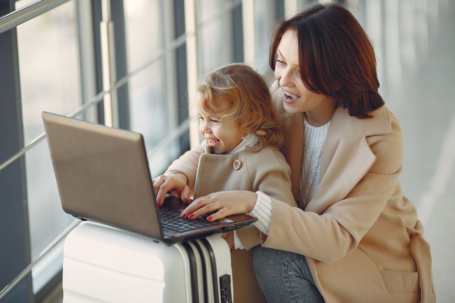 delighted mother with daughter typing on laptop in airport — Developers · Sweden: Island time, online time: ferries, beaches and full signal.