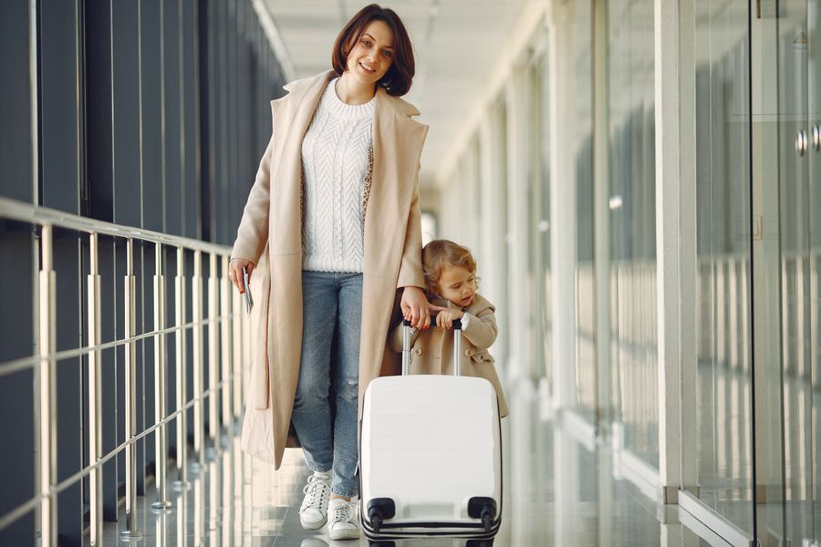 positive mother and daughter with suitcase in airport corridor — Developers · Luxembourg: Currency exchange, skipped: the phone pays at the real rate.
