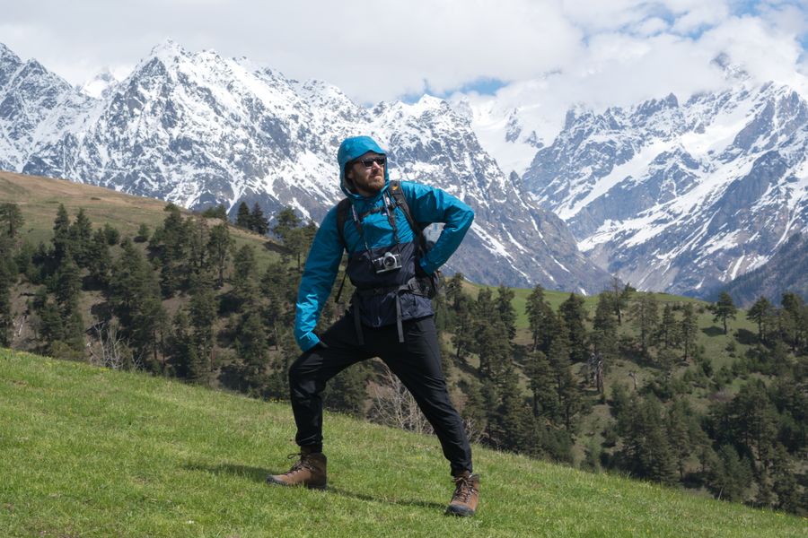man standing on a grass with snow covered mountains background — Developers · Iceland: The window seat office: emails sent somewhere over the ocean.