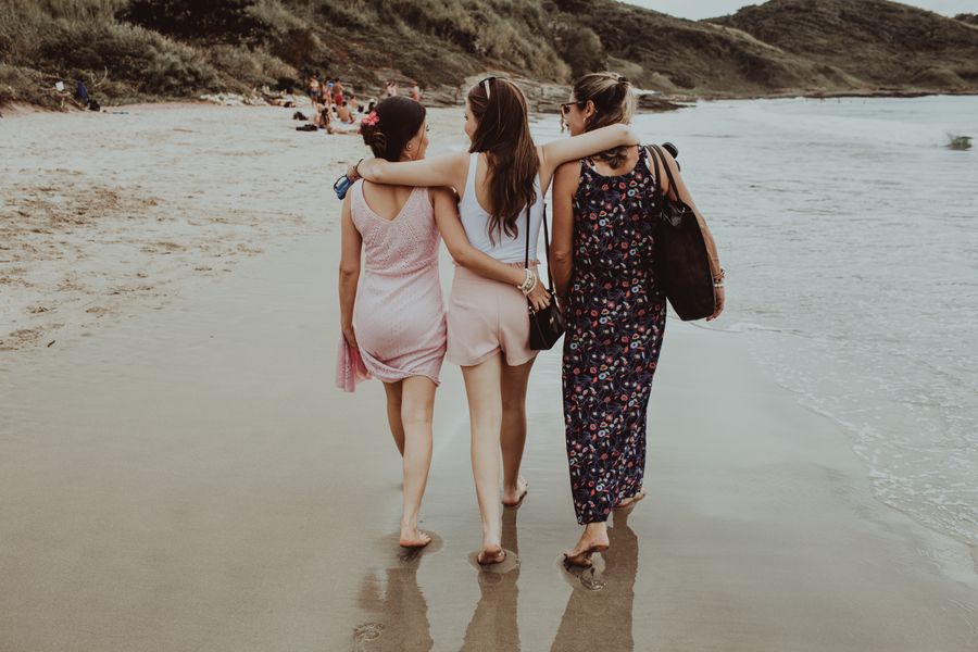 cheerful girlfriends walking together along sandy beach — Developers · Mexico: Check-in lines move faster when your documents are on your phone.