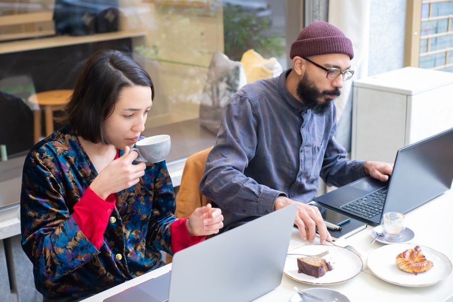 man and woman sitting in a cafe and using laptops while having a coffee and cake — Developers · Lesotho: Harbor views with full bars: coverage where travelers actually go.