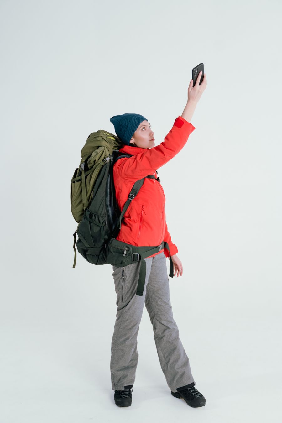 Young woman backpacker taking a selfie on a white background, dressed in outdoor gear. — Developers · Bosnia and Herzegovina: Café office: hotspot running, video call stable, no hotel Wi-Fi roulette.
