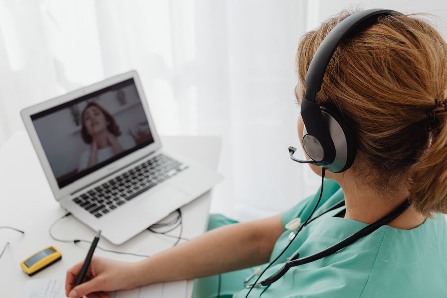 woman wearing headphones while video calling to patient — Support: Trailheads and lookouts: offline maps downloaded, just in case.