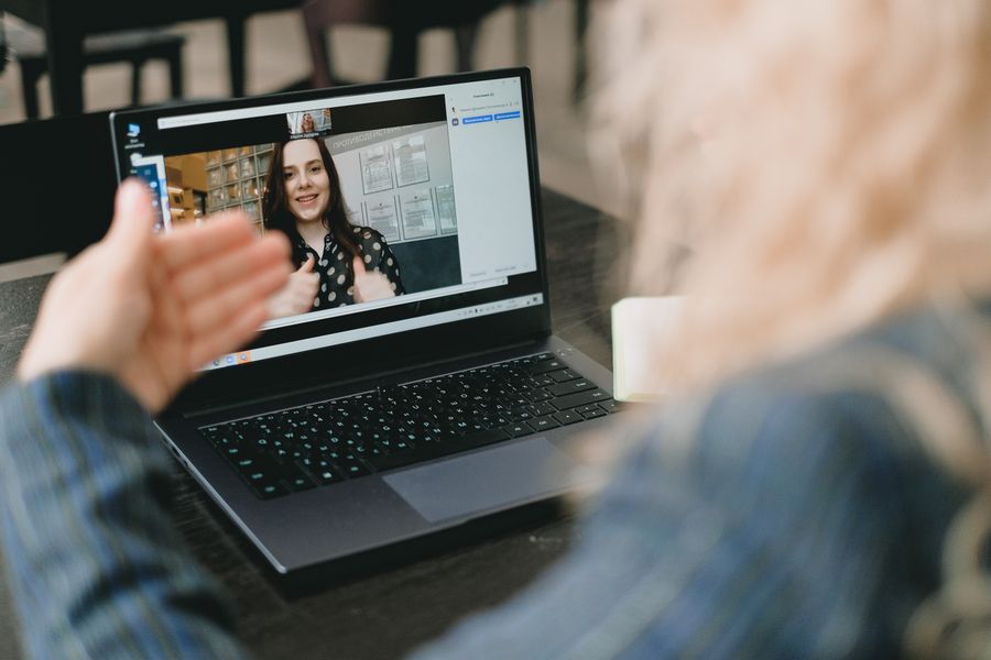female coworkers having video conference via netbook and discussing project — Developers · Poland: The last night: photo album backed up, memories safe before wheels-up.