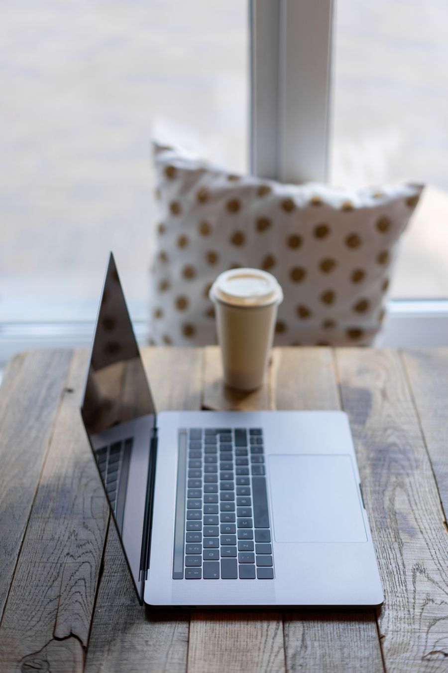 silver macbook on wooden table beside a paper cup — Terms: Border crossings without the paperwork shuffle: ID photos stored on the phone.