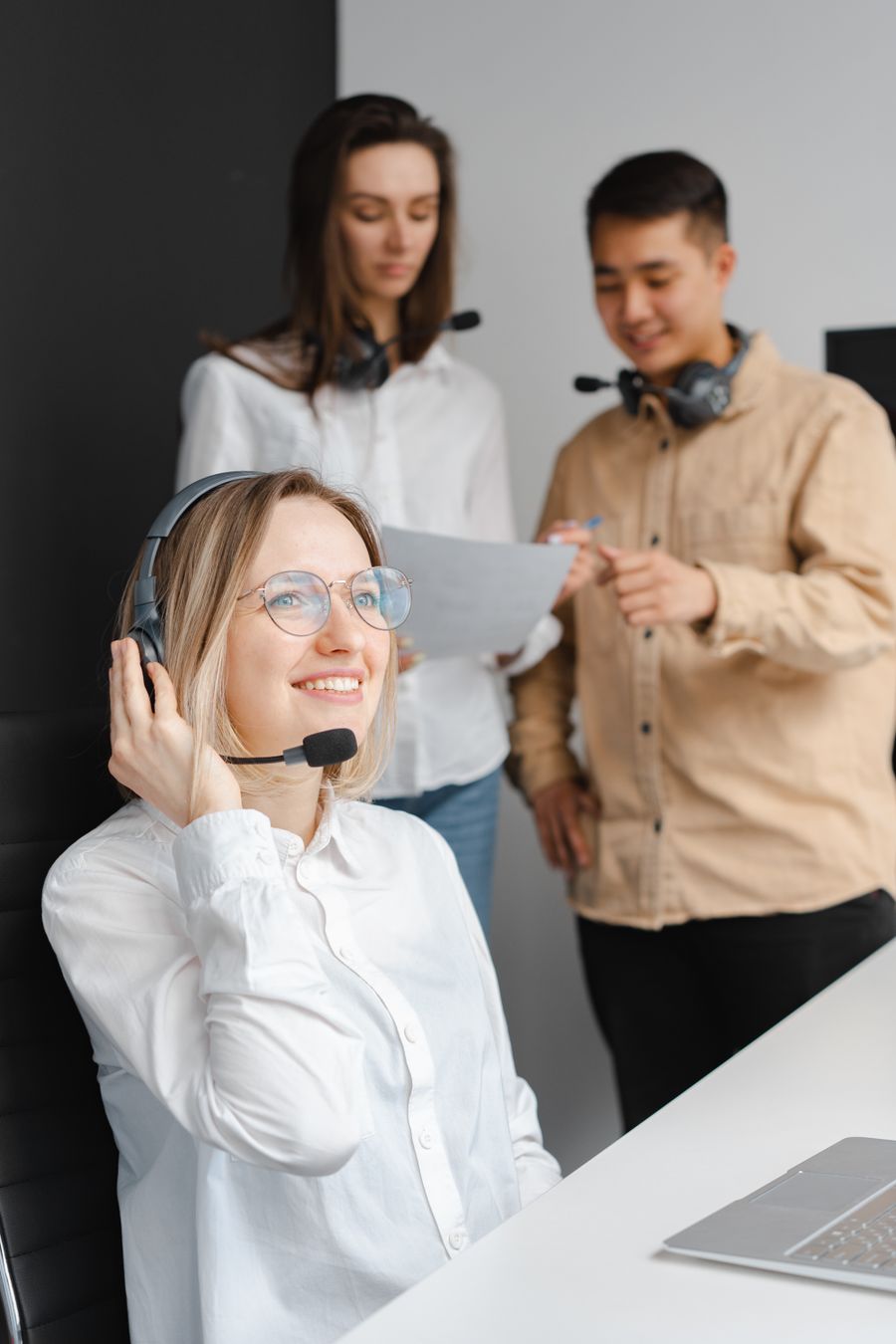 woman in a white shirt smiling while holding her headset — Developers · the United Kingdom: Check-in lines move faster when your documents are on your phone.