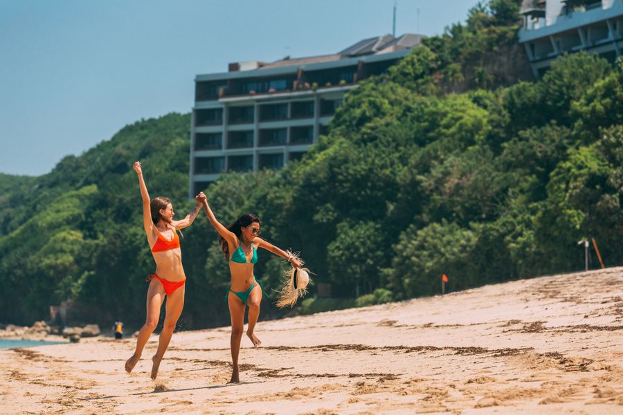 a pair of women in bikinis enjoying the beach — Developers · Qatar: Downtown, connected: the eSIM finds the fastest local network on its own.