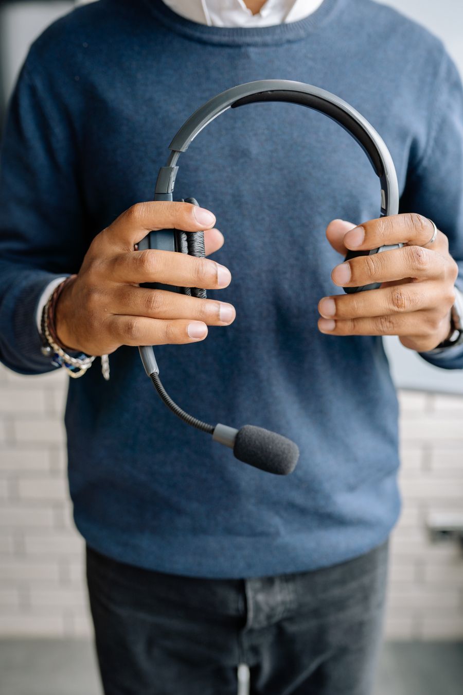 close up shot of a person in blue sweater holding a black headset — Developers · Denmark: The last night: photo album backed up, memories safe before wheels-up.