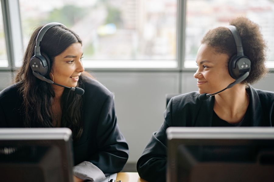 women in black blazer wearing headsets smiling at each other — Developers · Cuba: The commute, handled: podcasts downloaded, messages sent, no dead zones.