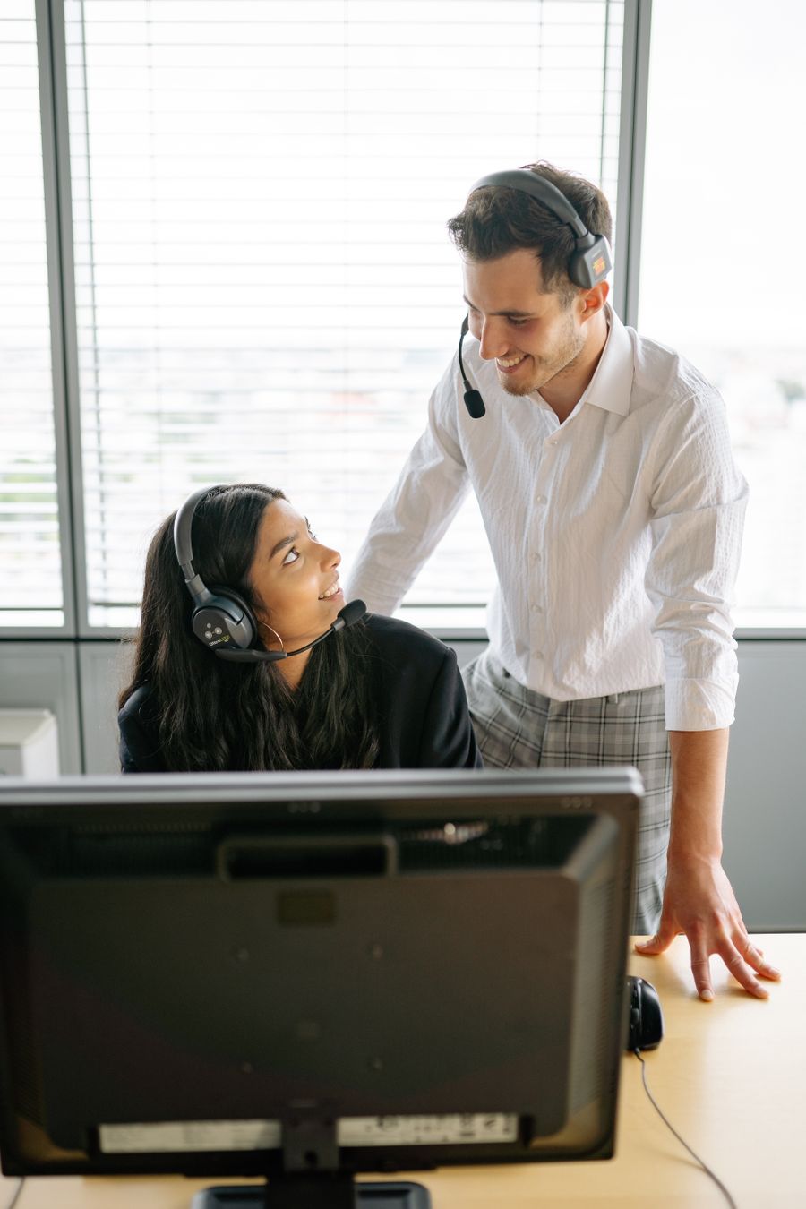 man and woman wearing black headset smiling at each other — Docs: No PDF manuals — the docs live where the product lives.