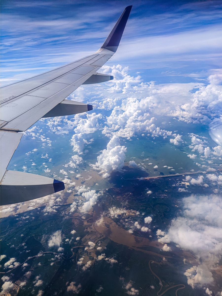 photo of an airplane wing over white clouds — Developers · Cuba: The conference badge: QR ticket scanned, session schedule synced.